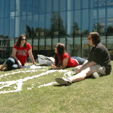 Student Sitting in Grass in Front of Library 
