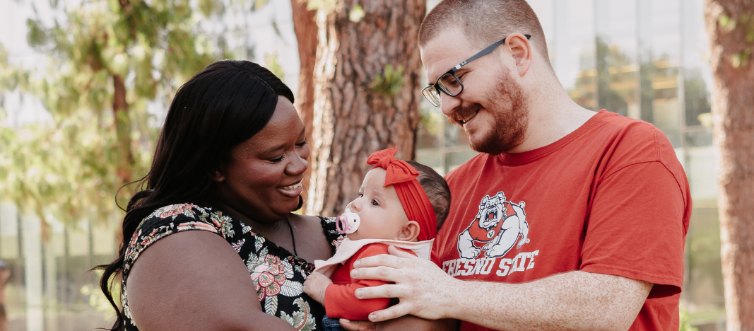 photo of two parents holding their child and smiling 