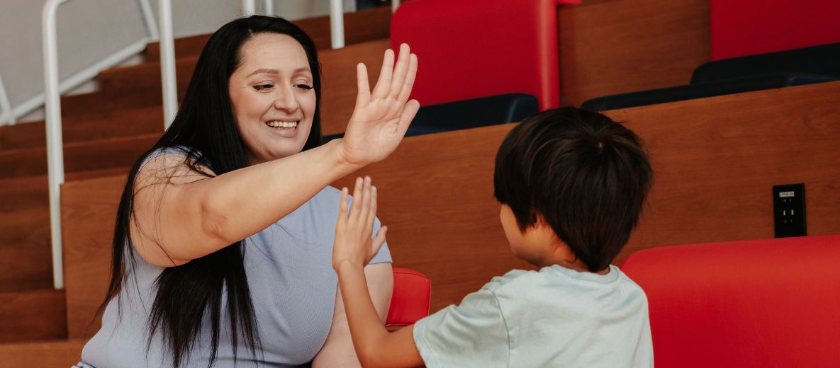 Photo of a parent high fiving their child and smiling while in the resnik student union at fresno state