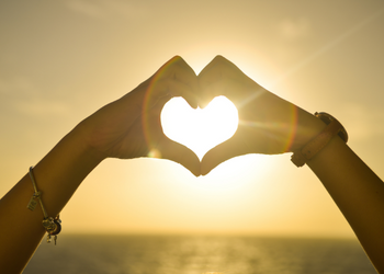 Two people holding up their hands and making a makeshift heart with their palms to show "love"