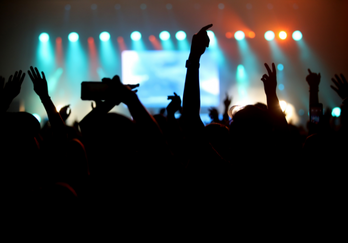 a nighttime concert event where people are dancing and putting their hands in the air