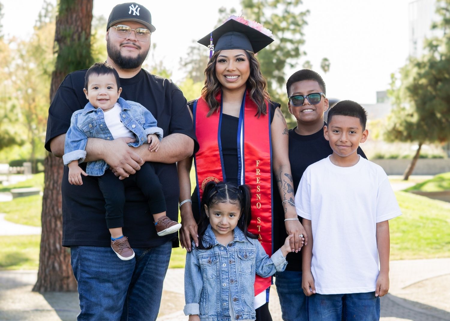 Maria and her family posing for a group photo and smiling by the Fresno State Library