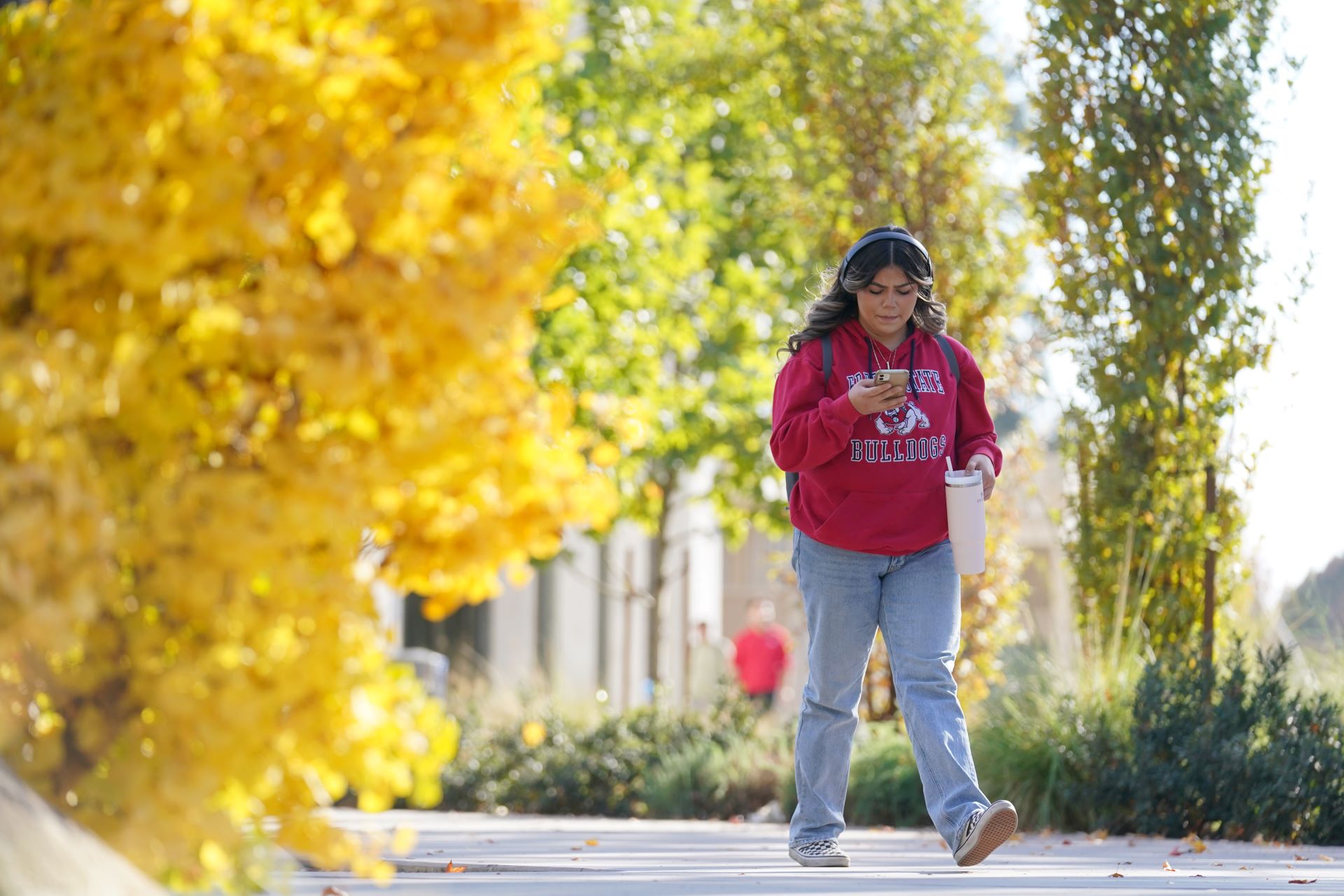 student walking looking at her cell phone