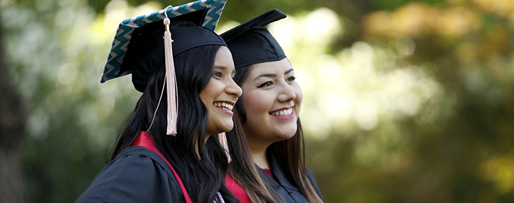Two Students Smiling Wearing Graduation Cap and Gowns