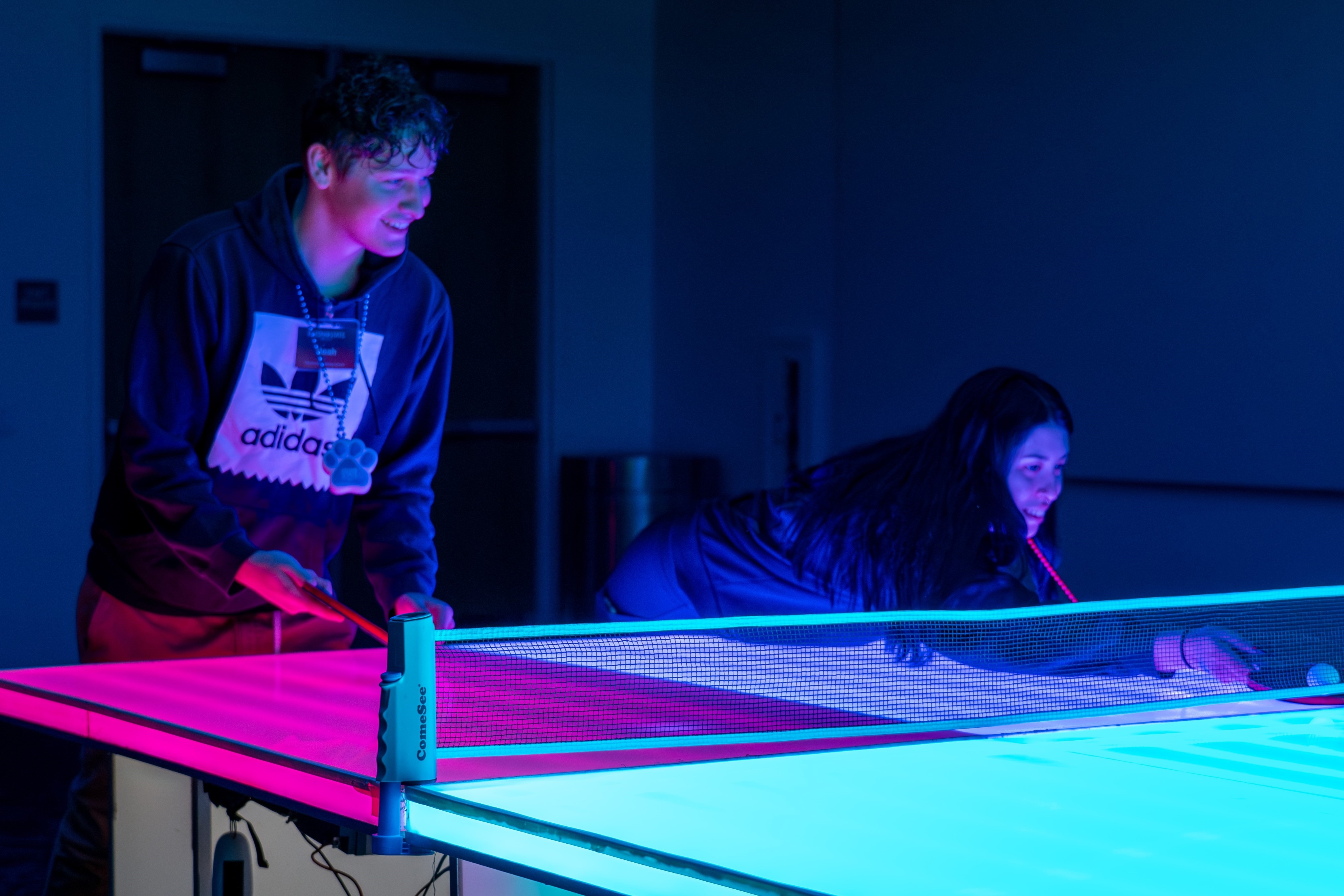 Two students playing glow-in-the-dark ping pong