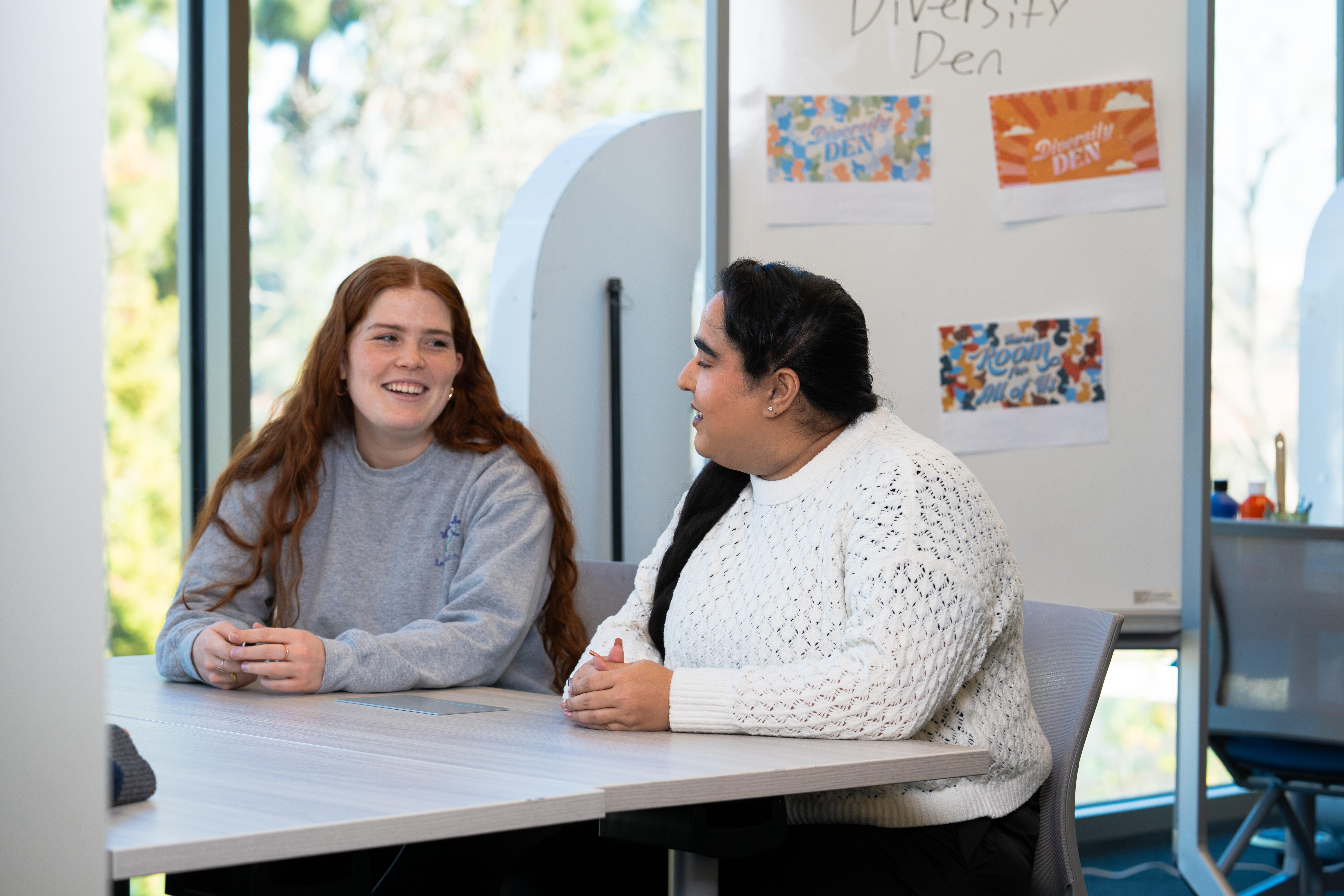 Two students sitting at a meeting table and talking