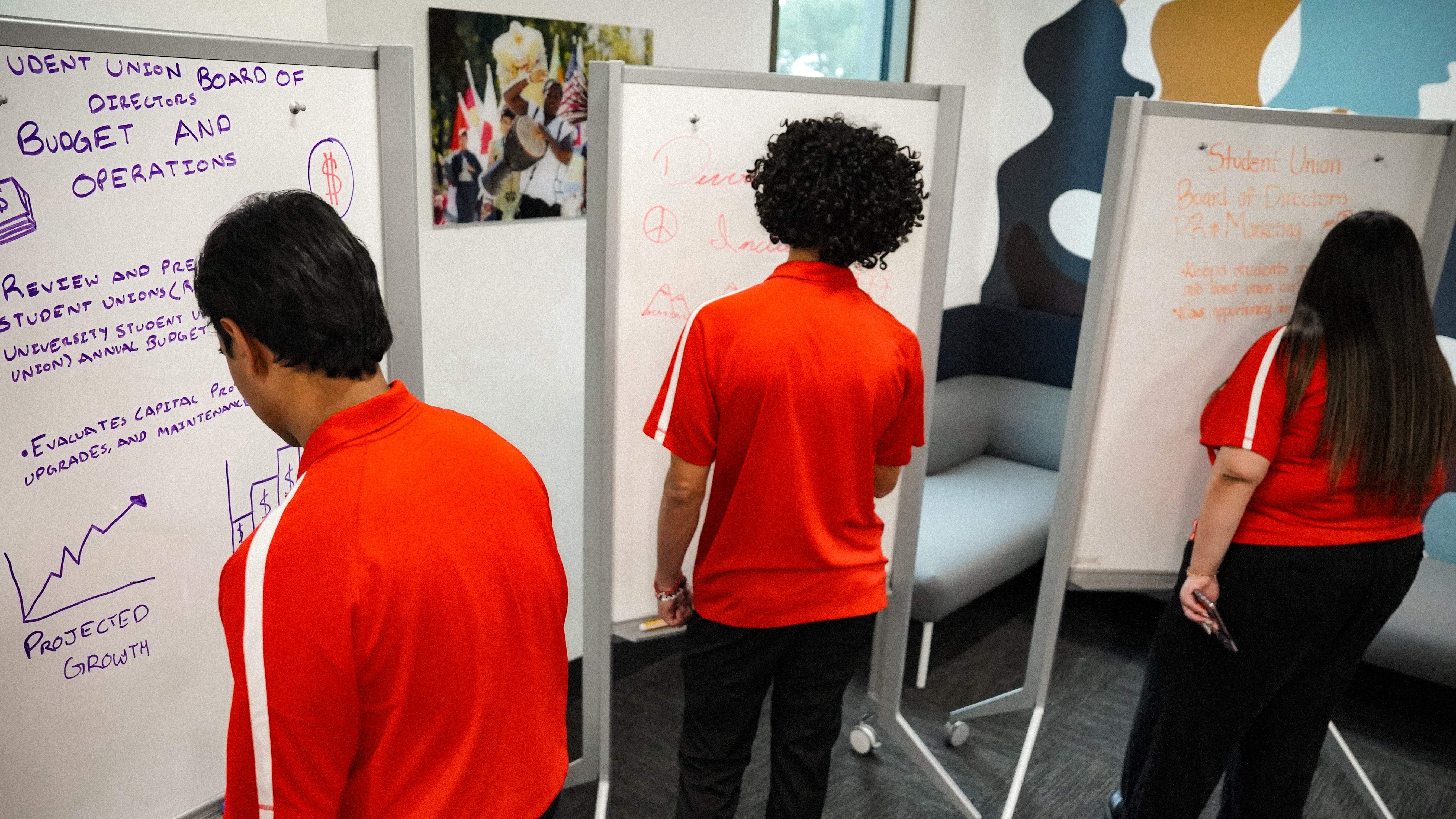 Three student leaders making plans on whiteboards