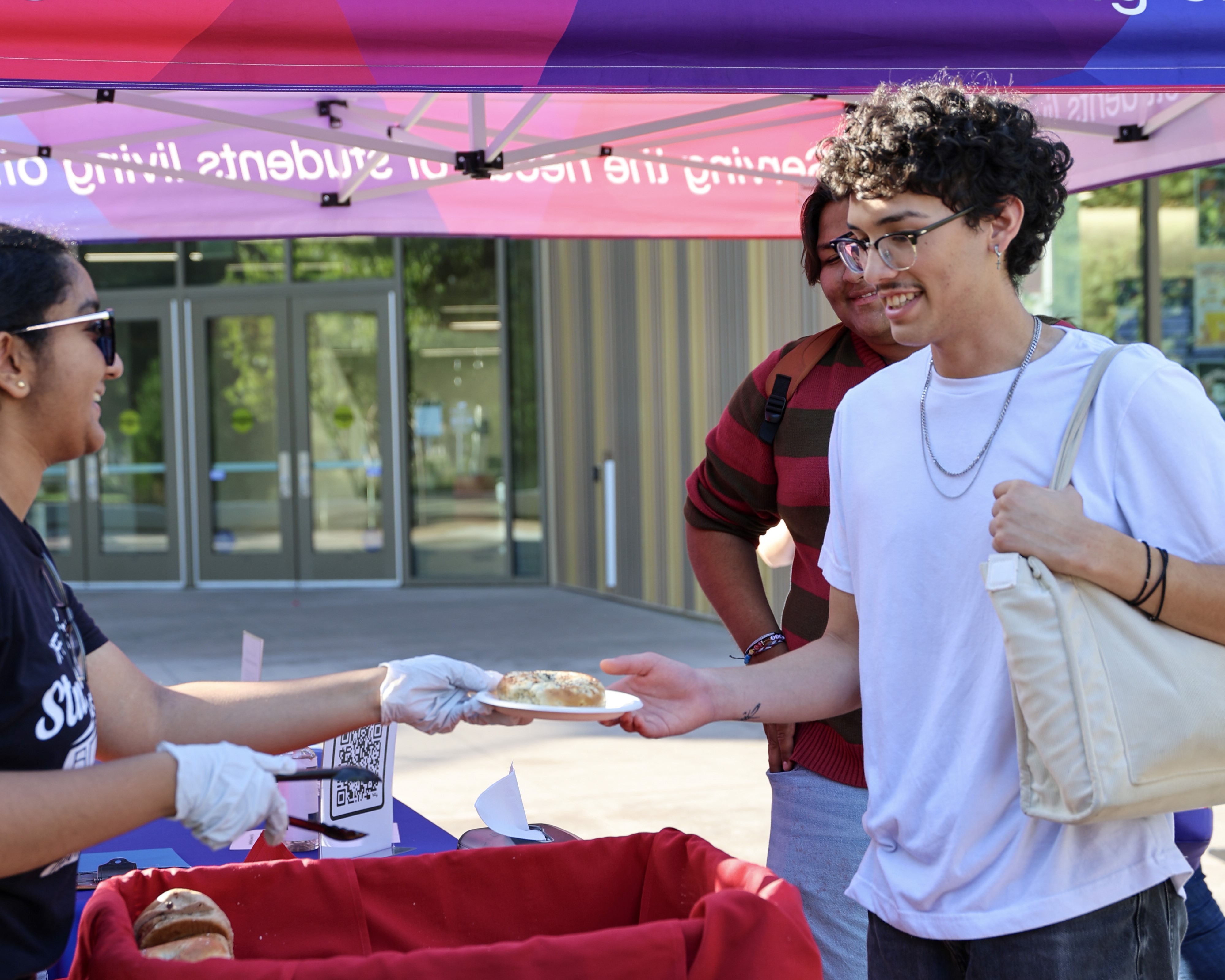 A Neighborhood Ambassador hands out bagels to commuter students in the morning