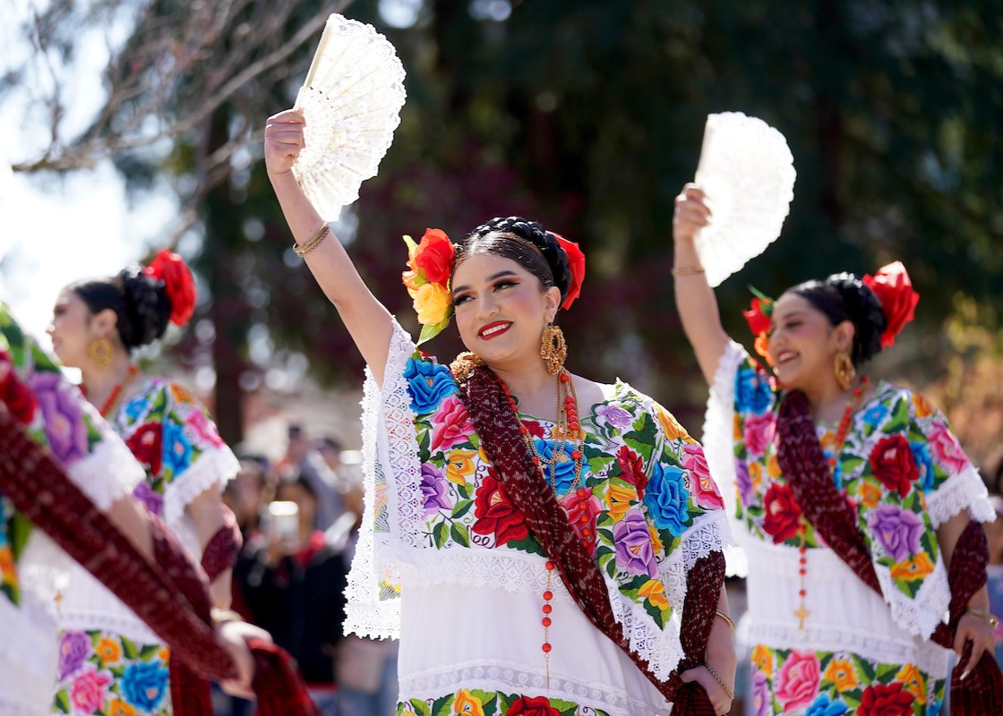 Folklorico dancers pose with their hand fans to the sky 