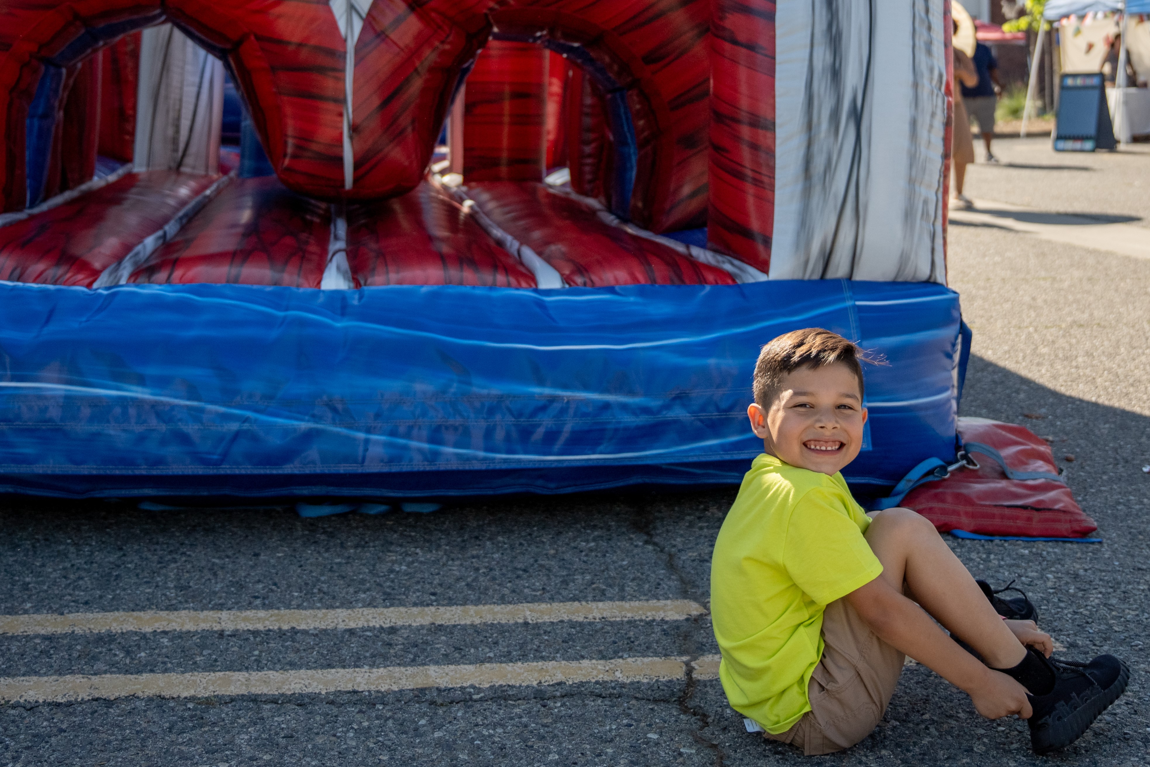 Little boy sitting on ground and smiling after playing in an inflatable