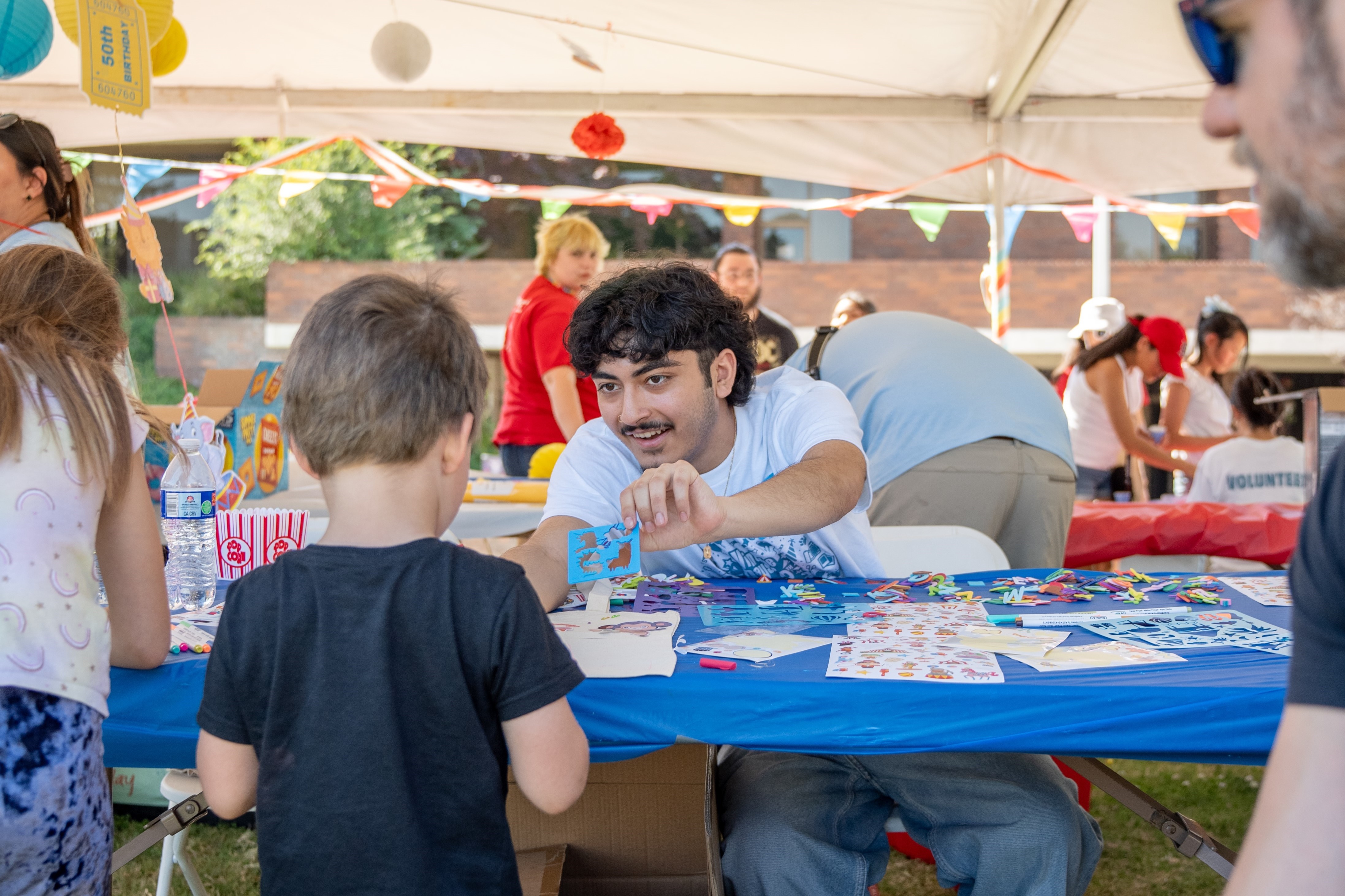 Vintage Days volunteer interacts with a kid at crafts table