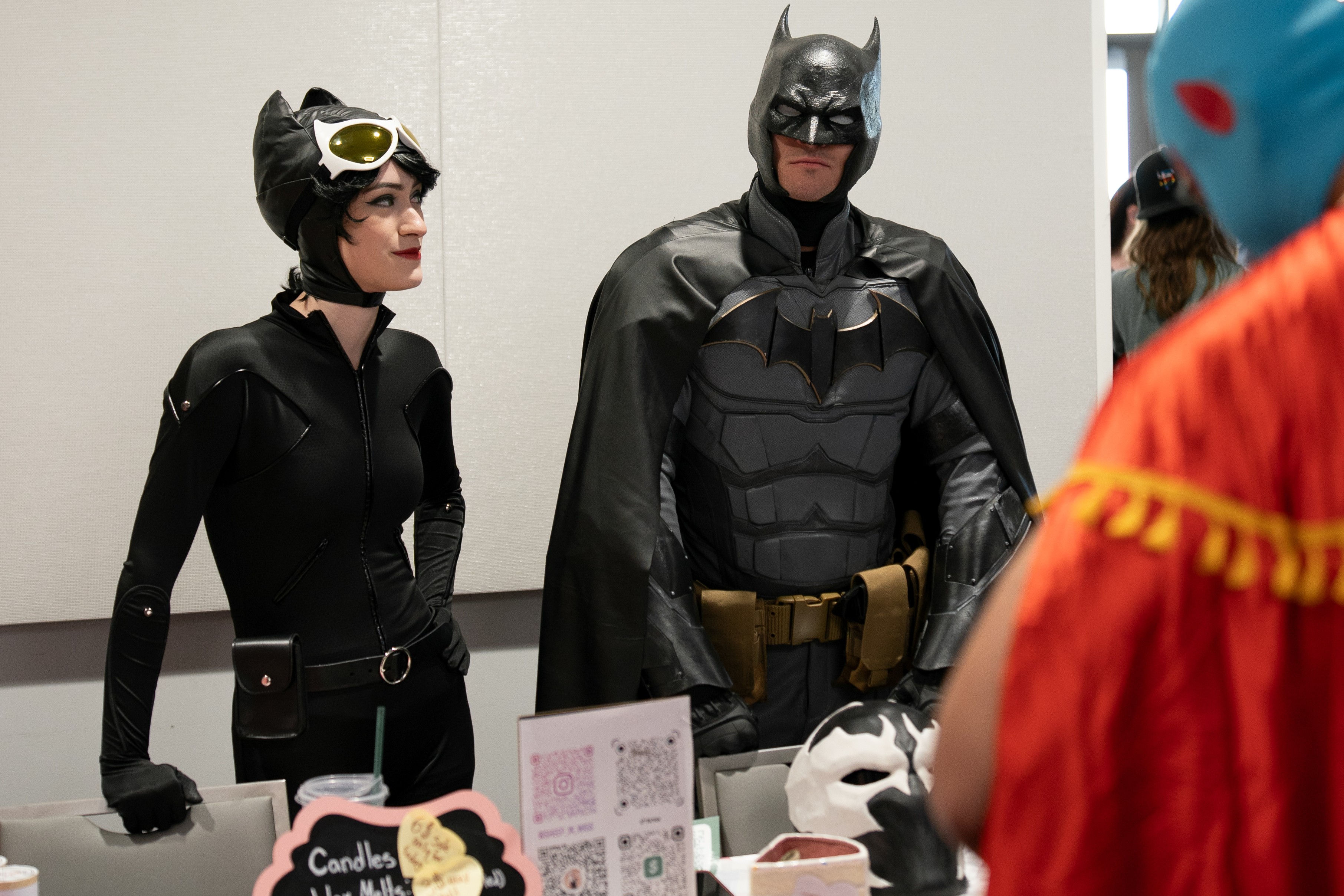 Catwoman and Batman cosplayers talking to a luchador cosplayer