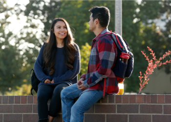 two students sittiing outside of the student health and counseling center smiling talking