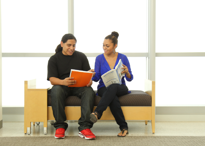 Two students with notebooks seated on a bench