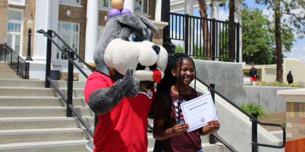 student smiling with Fresno State mascot