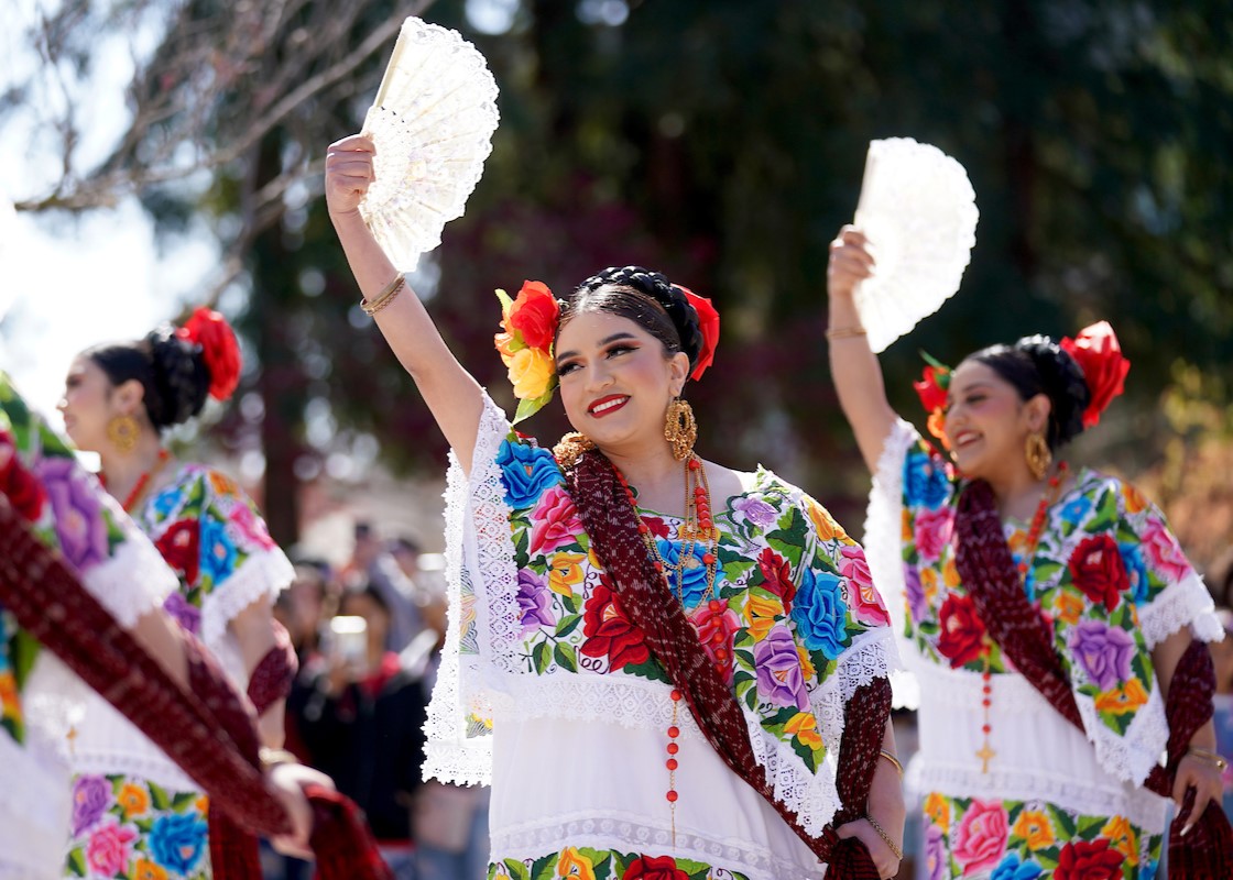 Folklorico dancers pose with their hand fans to the sky