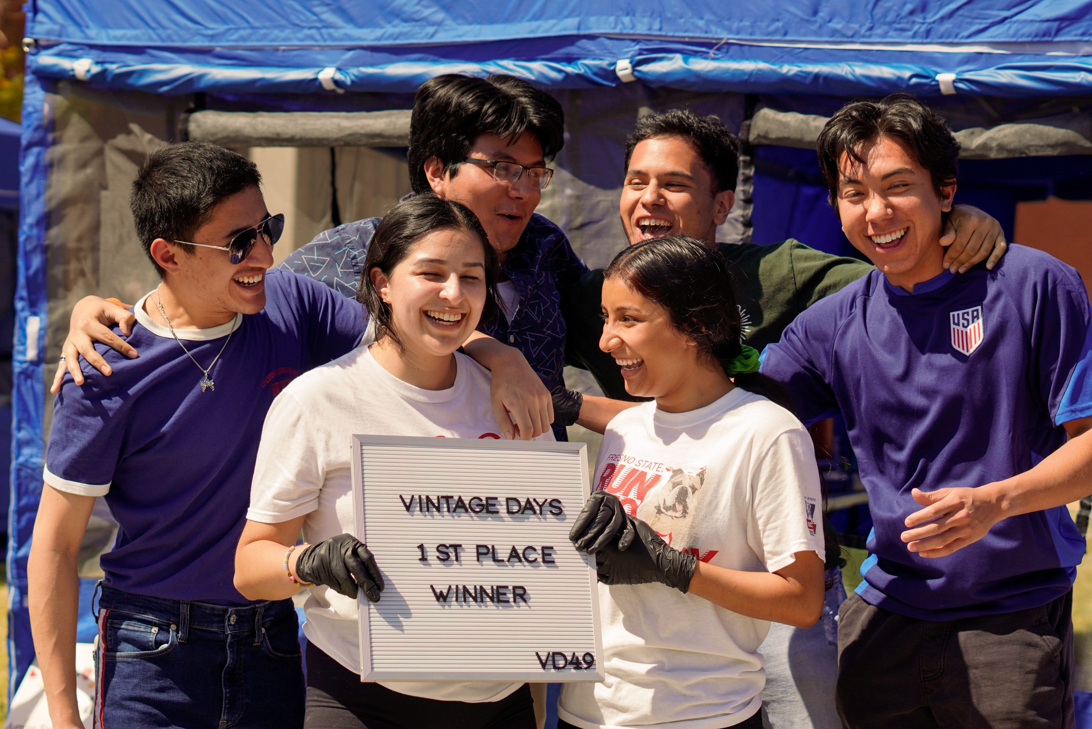 A student organization poses with their sign of victory in the food booth judging competition