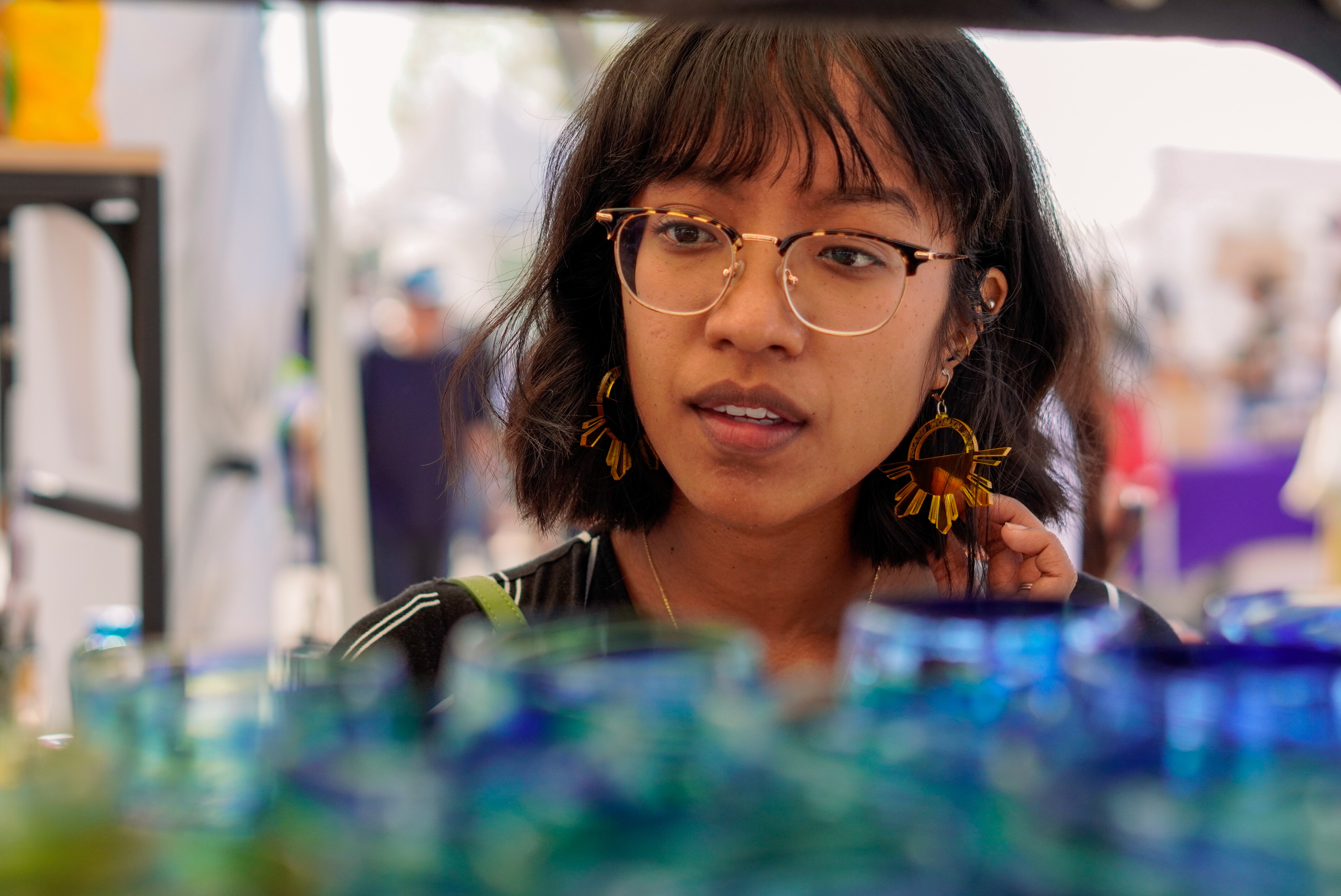 A student examines glassware at a Craft Faire's booth